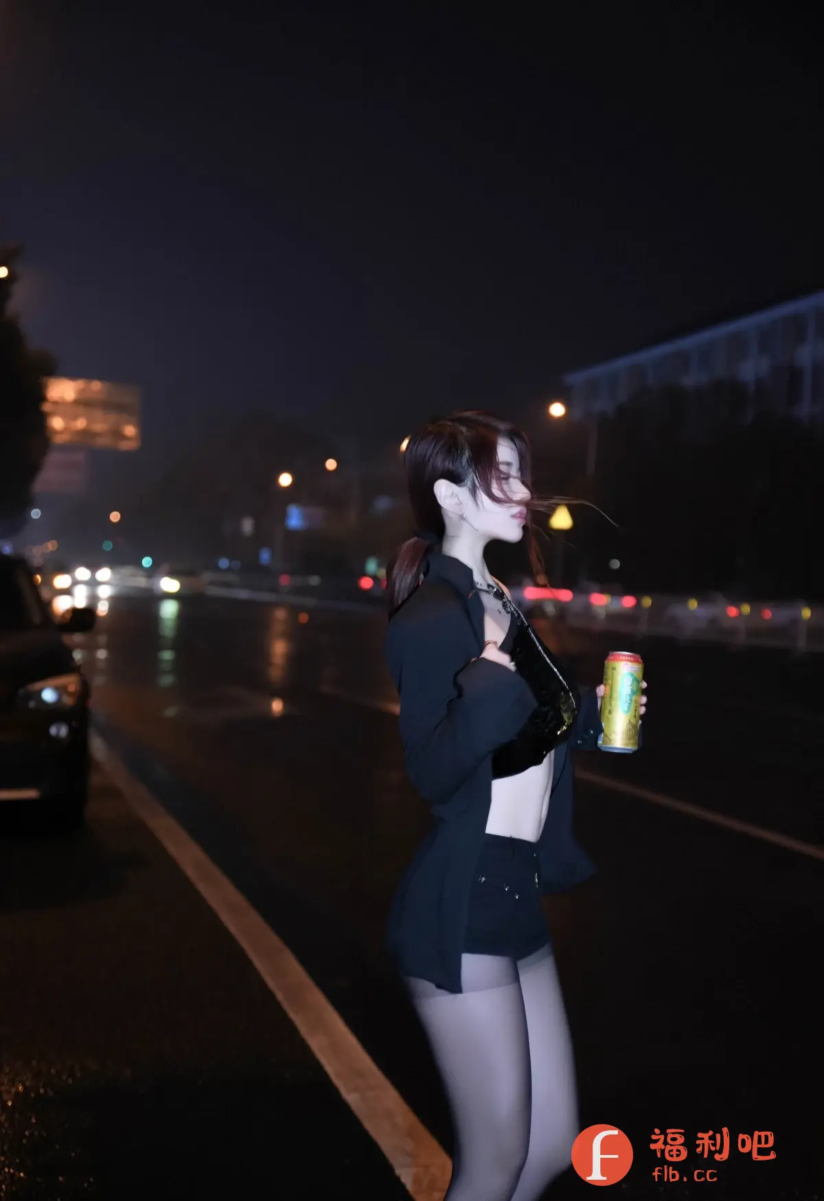 照片中,一位年轻的亚洲女性站在夜晚的街道上。她穿着黑色短裤套装,内搭露脐上衣,外披一件西装外套。她的头发扎成低马尾,几缕碎发散落在脸颊边,显得十分随性。她手持一罐饮料,侧身站立,目光看向远方。夜晚的街道湿漉漉的,路灯和车灯在地面上反射出光芒,营造出一种迷离的氛围。背景中可见模糊的建筑物和行驶的车辆,增添了都市感。整体风格时尚而性感,展现了现代女性的自信和魅力。