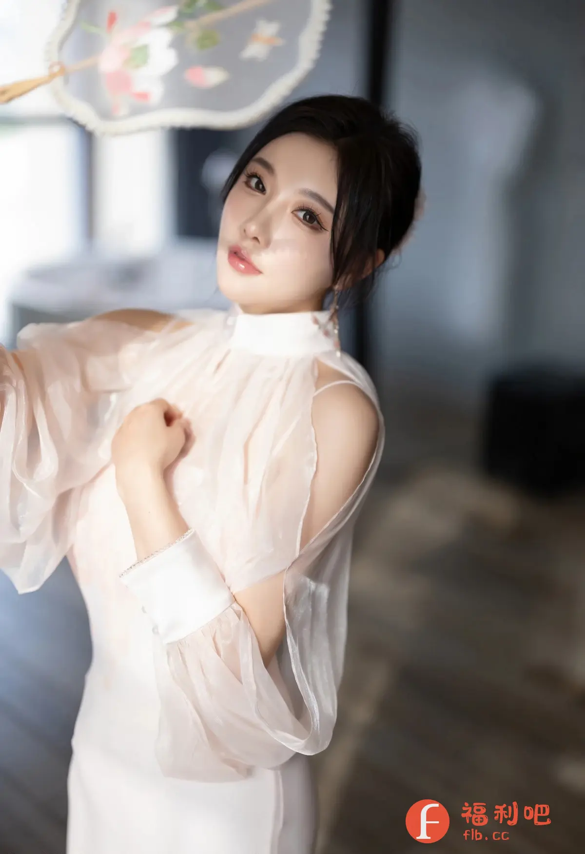 这张照片是一张女性的私房写真照片。照片中的女性是一位美丽的亚洲女性，她有着精致的五官，光滑的皮肤和一头乌黑亮丽的头发。她身穿一件设计独特的白色连衣裙，连衣裙的袖子是透明的，带有褶皱的设计，显得非常优雅和时尚。她手持一把带有花朵图案的扇子，增添了一丝古典韵味。她的姿势优雅，眼神温柔，散发出一种迷人的魅力。照片的光线柔和，背景虚化，更加突出了人物的美丽。整体构图和谐，色彩柔和，给人一种温馨舒适的感觉。这张照片完美地展现了女性的美丽和优雅，是一张高质量的艺术作品。