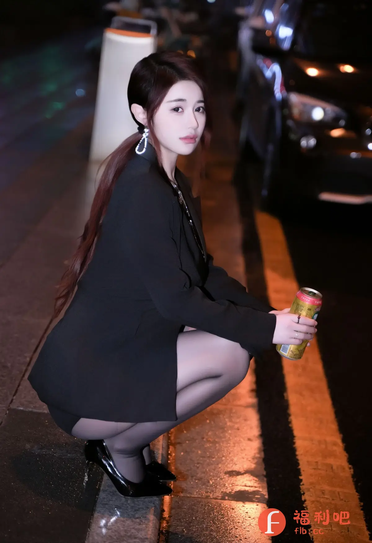照片中是一位年轻漂亮的亚洲女性。她蹲在路边,身穿黑色西装外套,内搭黑色短裙,脚穿黑色高跟鞋,腿上穿着黑色丝袜,整体造型性感时尚。她留着棕红色的长发,扎成低马尾,戴着闪亮的耳环。她手持一罐饮料,神情略带忧郁,眼神迷离地注视着镜头。背景是夜晚的街景,路面湿漉漉的,反射着路灯的光芒,营造出一种朦胧而浪漫的氛围。整体画面充满了时尚感和性感魅力,同时又透露着一丝孤独感,引人遐想。