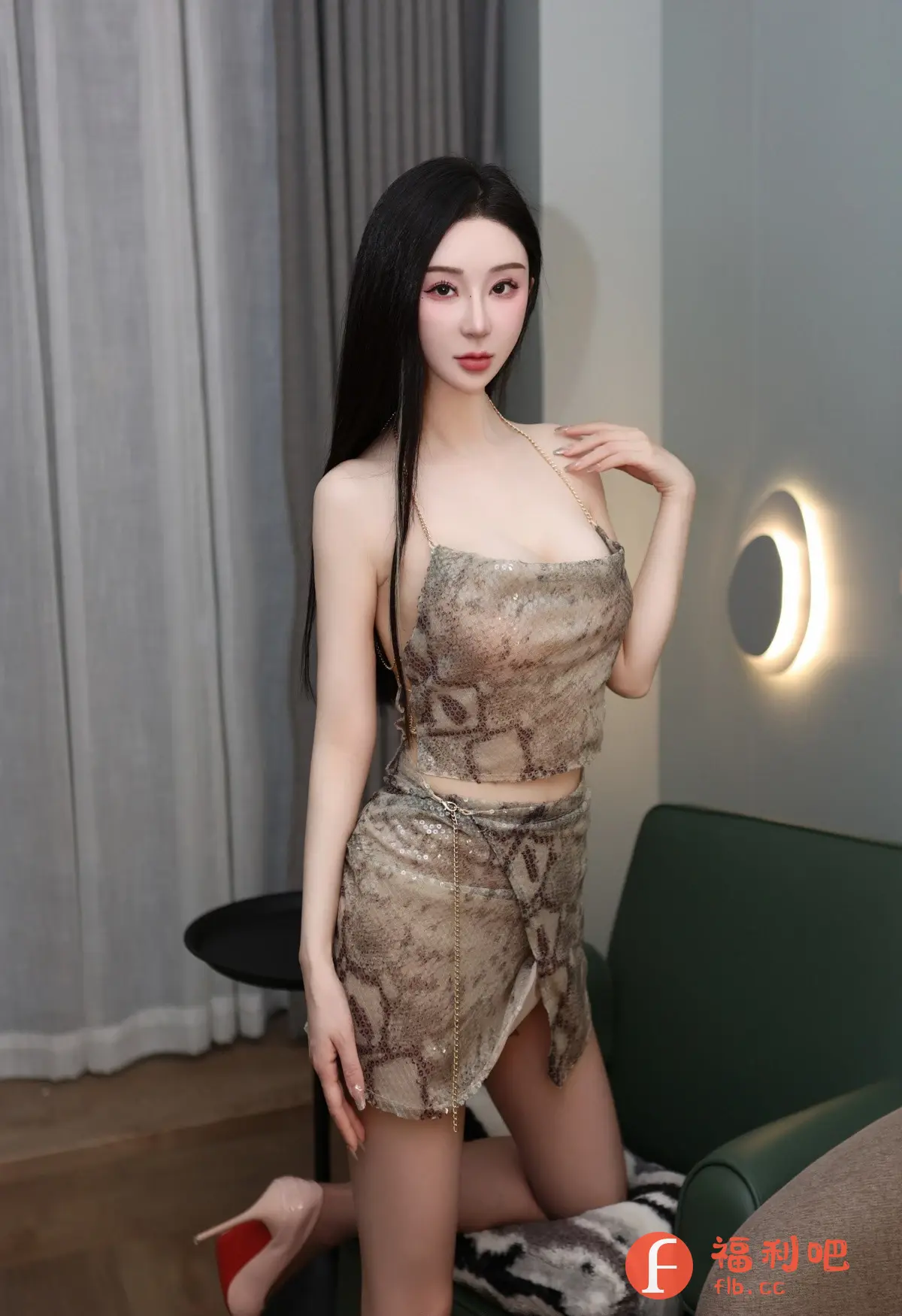 照片中一位穿着时尚的年轻女性跪在椅子上,对着镜头摆姿势。她身穿一套蛇纹图案的露脐上衣和短裙,裙子设计别致,带有侧开衩,展现了她修长的双腿。上衣由金色细链肩带连接,更显性感迷人。她脚上穿着一双裸色高跟鞋,鞋底为红色,增添了一抹亮色。她的长发乌黑亮丽,自然垂落在肩上,精致的妆容凸显了她的美貌。背景简洁,有窗帘、沙发、小桌子和壁灯,营造出一种温馨舒适的氛围。整体构图和光线运用突出了人物,是一张充满魅力和时尚感的写真照片。