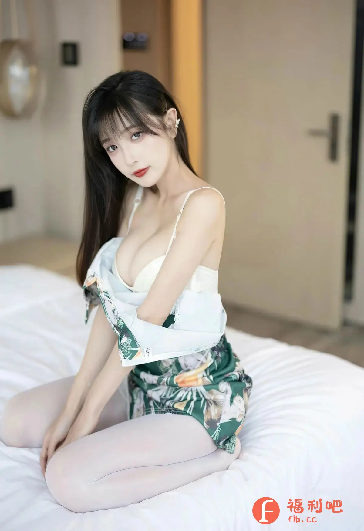 描述：照片中一位年轻的亚洲女性跪坐在白色的床单上，她乌黑的长发自然地披散在肩上，刘海整齐地遮盖着额头。她的皮肤白皙，化着精致的妆容，红唇格外醒目，眼神略带妩媚。她身穿一件白色内衣，外面套着一件绿色花纹的睡袍，睡袍半褪，露出迷人的锁骨和部分胸部。她的姿态性感而慵懒，似乎刚刚醒来。背景是简约的房间，白色的墙壁和门，以及模糊的装饰品，营造出一种私密而舒适的氛围。整体画面充满了女性的柔美和性感，同时也透露出一种淡淡的忧郁。