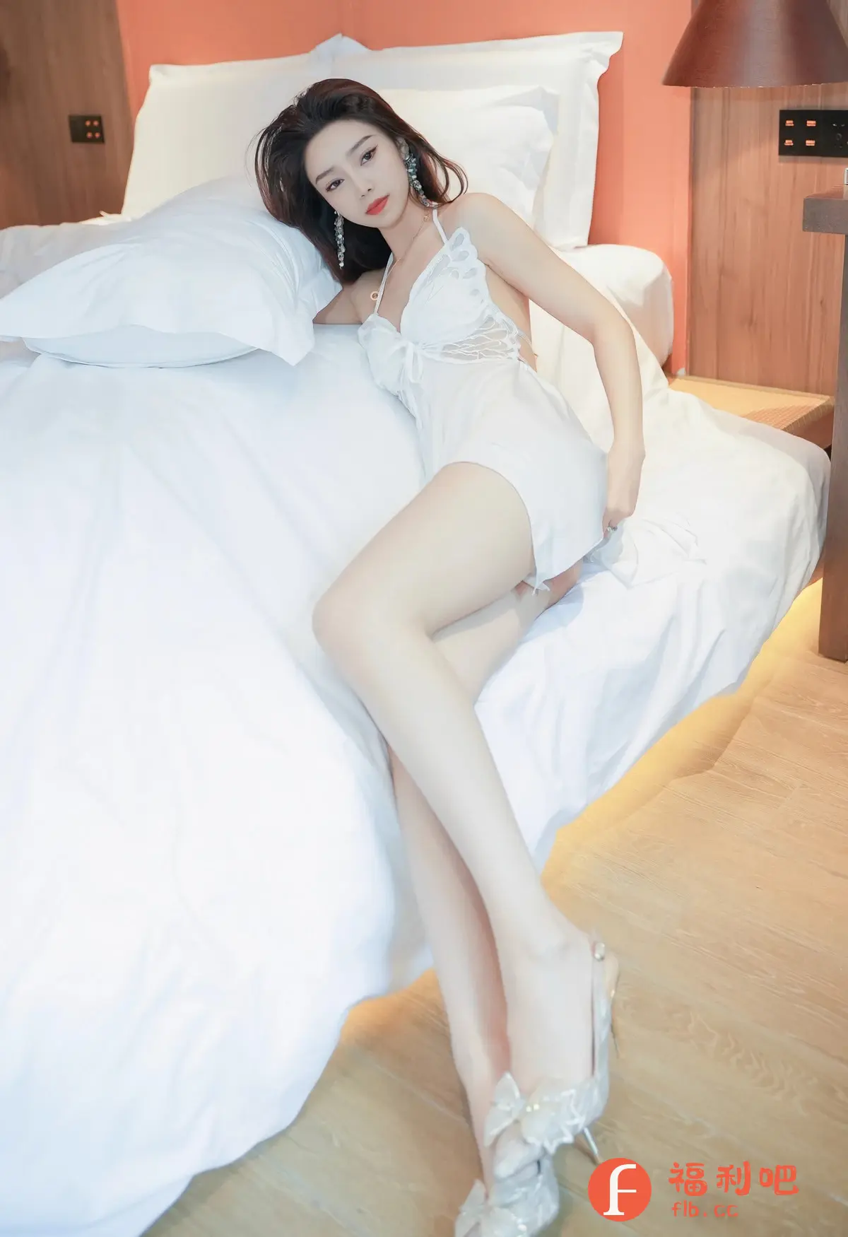 描述:照片中,一位亚洲美女穿着性感白色吊带睡裙,慵懒地躺在铺着洁白床单的床上。她姿态妩媚,眼神略带挑逗,精致的妆容和耳环更显成熟风韵。一双修长的美腿交叉,脚上穿着水晶高跟鞋,整体营造出一种性感、撩人的氛围。背景简洁,以白色床单和木质地板为主,更突显了美女的妩媚动人。这无疑是一张私房写真,展现了女性性感的一面。