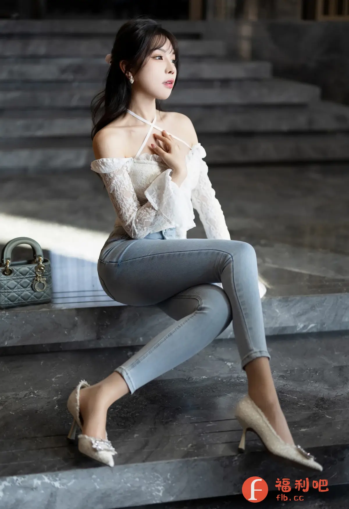 描述:照片中是一位年轻漂亮的亚洲女性,她正坐在一个灰色大理石楼梯上,姿态优雅迷人。她穿着一件白色蕾丝露肩上衣,搭配浅蓝色紧身牛仔裤,脚踩一双镶有水钻的浅色高跟鞋,整体造型时尚精致。她的长发随意地披在肩上,脸上化着精致的淡妆,眼神温柔,微微抬起的下巴展现出优美的颈部线条。在她身旁放着一只灰绿色的小手提包,增添了几分优雅气息。整个画面背景简约,光线柔和,营造出一种宁静而美好的氛围,突显了女性的柔美和魅力。