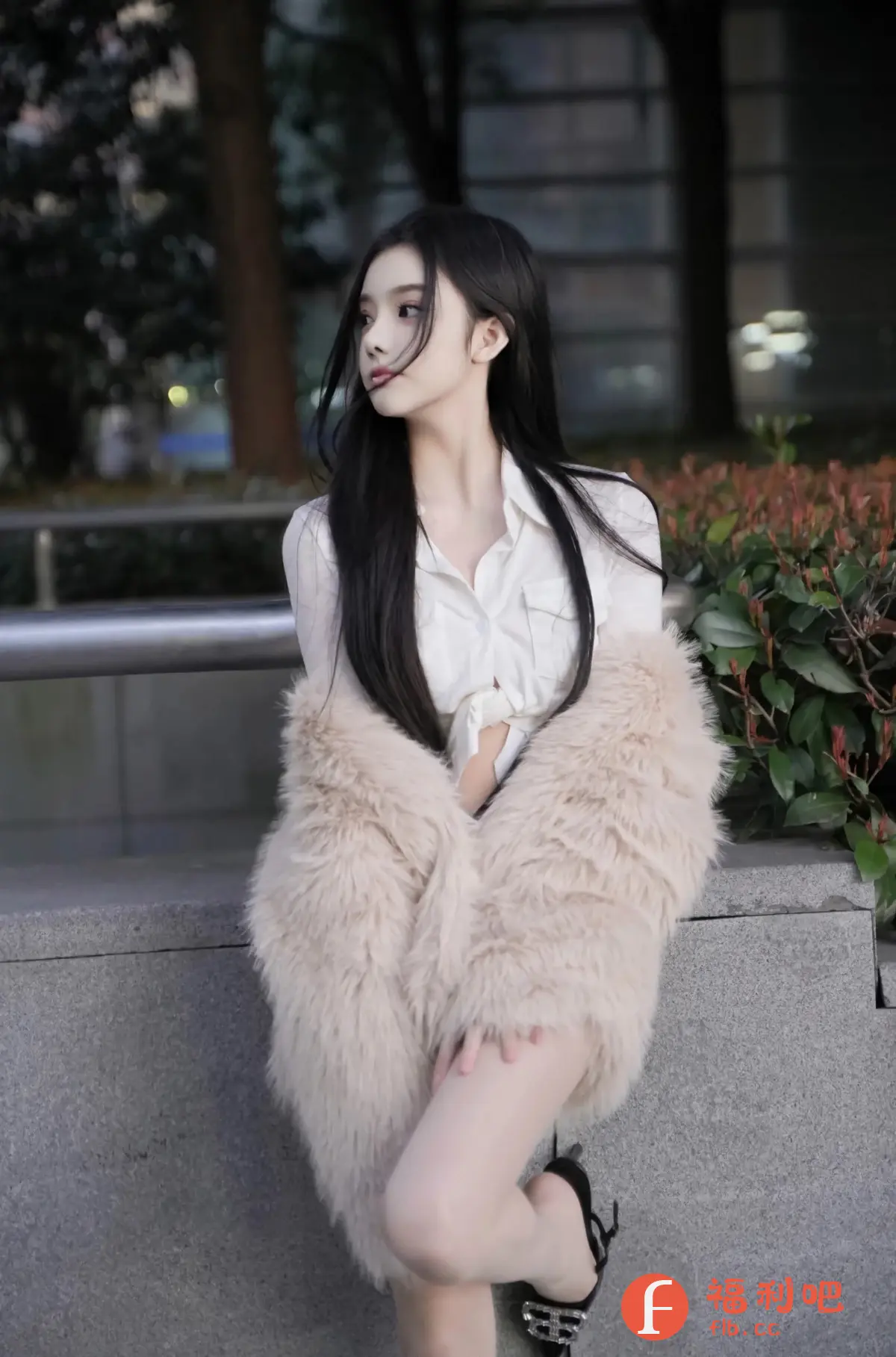这位美女穿着一件白色衬衫和一件毛绒外套,衬衫的下摆被扎成了一个可爱的结。她的头发乌黑亮丽,随意地披散在肩上,几缕发丝随风飘动,更显妩媚动人。她侧着头,眼神温柔,似乎在欣赏着远处的风景。照片的背景是一些绿植和模糊的灯光,营造出一种宁静而浪漫的氛围。她坐在一个石质的平台上,双腿交叠,穿着一双别致的黑色高跟鞋,更显身材修长。整体照片风格清新自然,突显了美女的清纯气质和时尚品味,让人赏心悦目。
