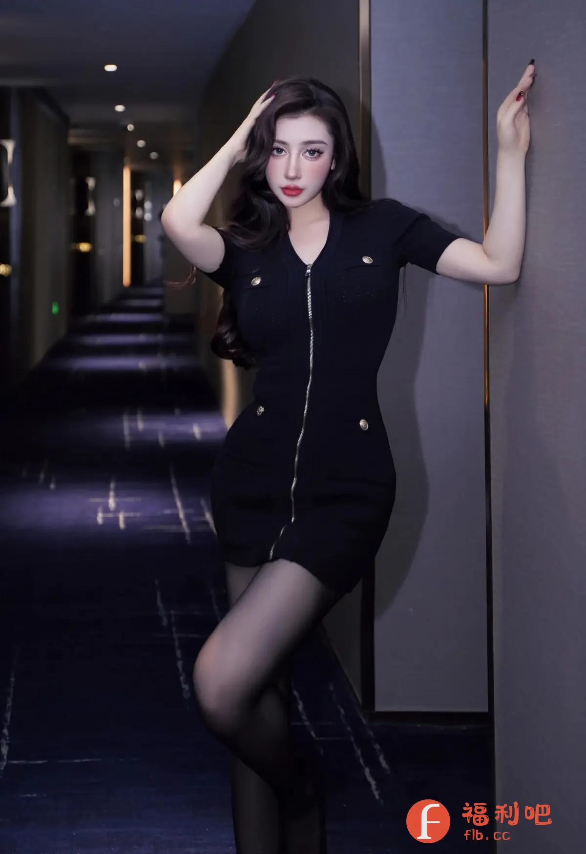 照片中,一位身材姣好的年轻女性身着一袭精致的黑色连衣裙,搭配黑色丝袜,展现出优雅而性感的气质。连衣裙的设计别具匠心,纽扣和拉链的细节增添了时尚感。她倚靠在墙边,一只手优雅地放在头顶,另一只手随意地搭在墙上,姿态妩媚动人。背景是一个深色的走廊,灯光略显昏暗,营造出一种神秘而私密的气氛。她的妆容精致,红唇尤其醒目,更凸显了她的魅力。整体画面充满着女性的柔美和自信,散发着迷人的吸引力。