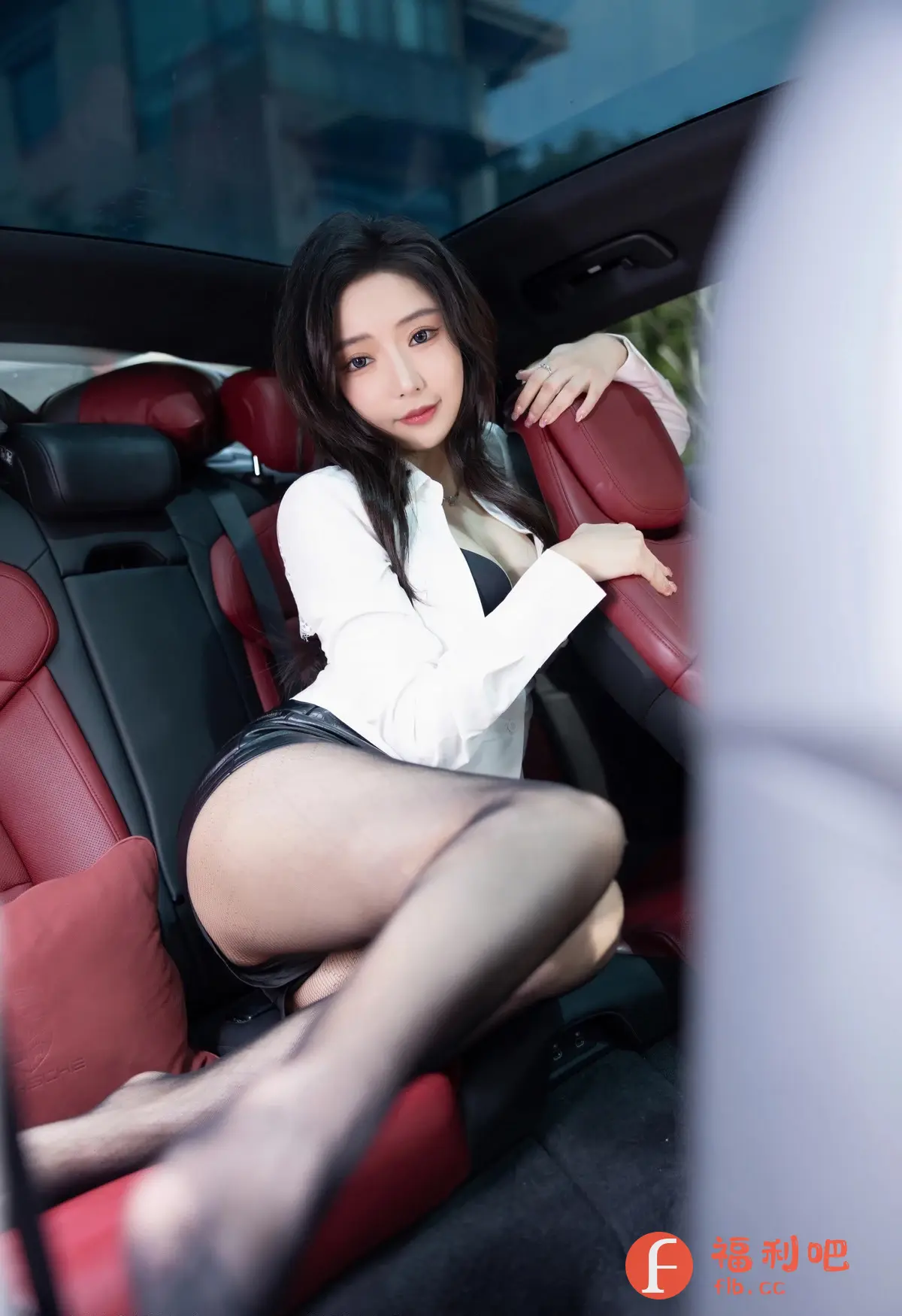 描述:照片中,一位年轻女子坐在汽车的后座上,她穿着一件宽松的白色衬衫,内搭黑色文胸,下身穿着黑色皮短裤,搭配着性感的黑色丝袜。她的姿势随意而迷人,一只手搭在座椅靠背上,另一只手自然地放在腿上。她的眼神充满魅力,微微上扬的嘴角带着一丝微笑。红色的汽车座椅与她的装扮形成了鲜明的对比,更凸显了她的性感和诱惑。照片整体的光线柔和,突出了人物的轮廓和肤色,营造出一种私密而温馨的氛围。