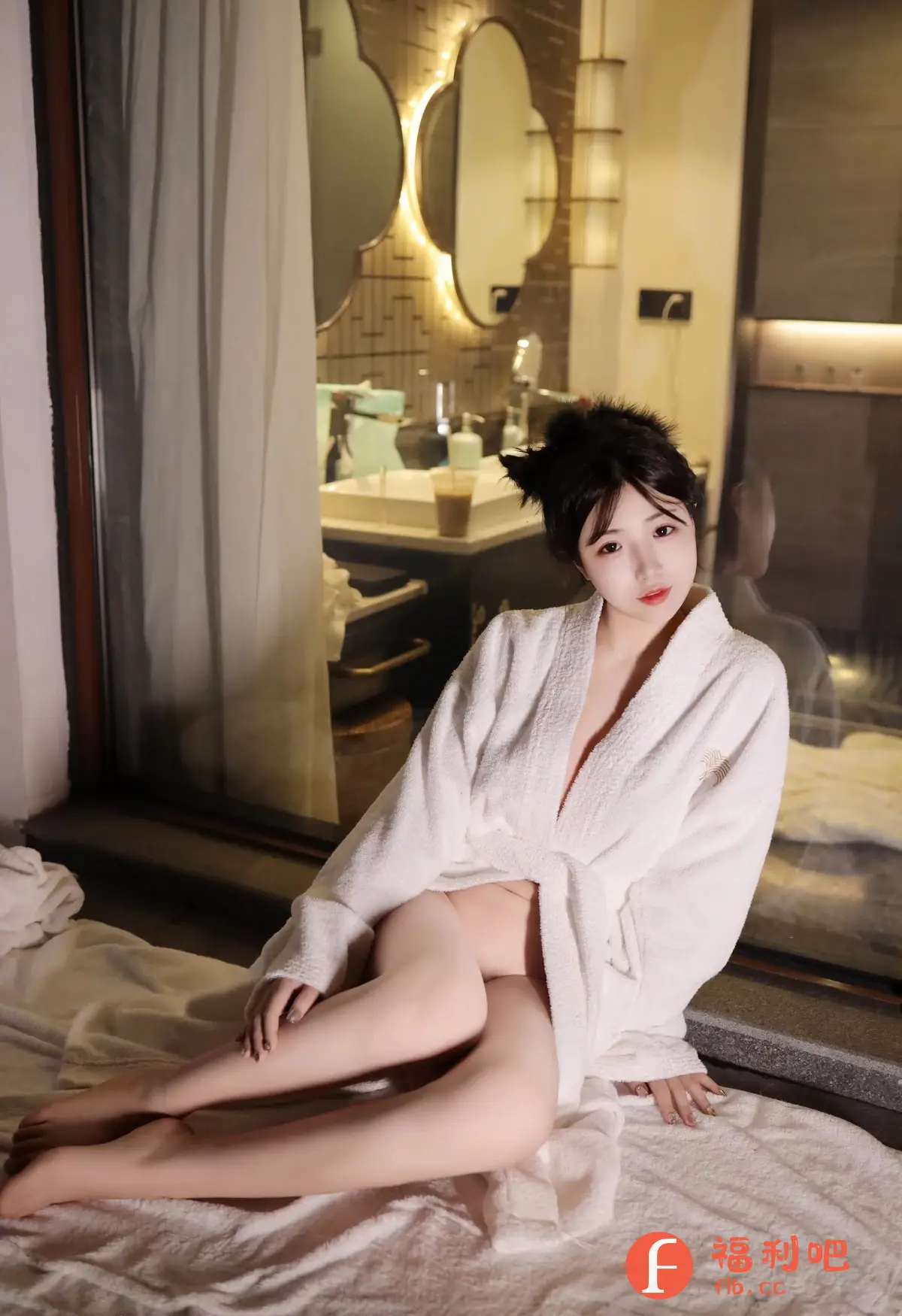 描述:照片中一位年轻女性穿着白色浴袍,坐在白色床单上。她姿势随意,浴袍略微敞开,露出部分腿部肌肤。她的头发梳成俏皮的发型,配有猫耳朵发饰,增添了一丝可爱气息。背景是一个现代化的浴室,透过窗户可以看到内部的装饰和灯光,营造出一种温馨而私密的氛围。整体色调柔和,光线分布均匀,突出了女性的柔美和放松的状态。