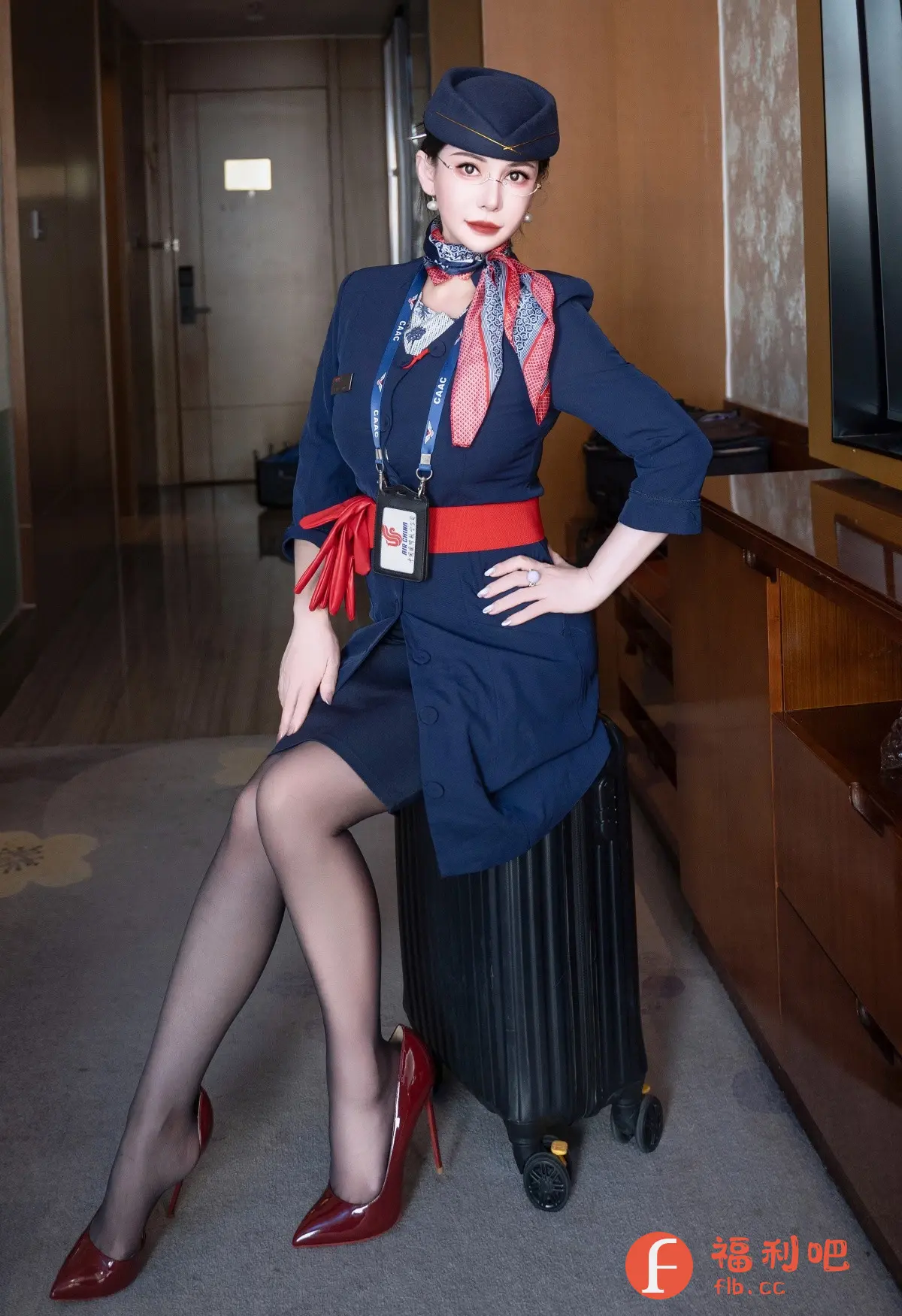 这张照片展现了一位身着空乘制服的美女。她头戴深蓝色制服帽,颈间系着色彩鲜艳的丝巾,上身穿着一件蓝色制服外套,搭配一条醒目的红色腰带。她的左手随意地搭在腰间,右手戴着一枚戒指。下身穿着黑色丝袜和一双亮红色高跟鞋,显得既优雅又性感。她坐在一个黑色的行李箱上,背景是酒店房间的走廊和家具,整体画面时尚而有气质,展现了空乘人员的专业形象和个人魅力。:识别内容