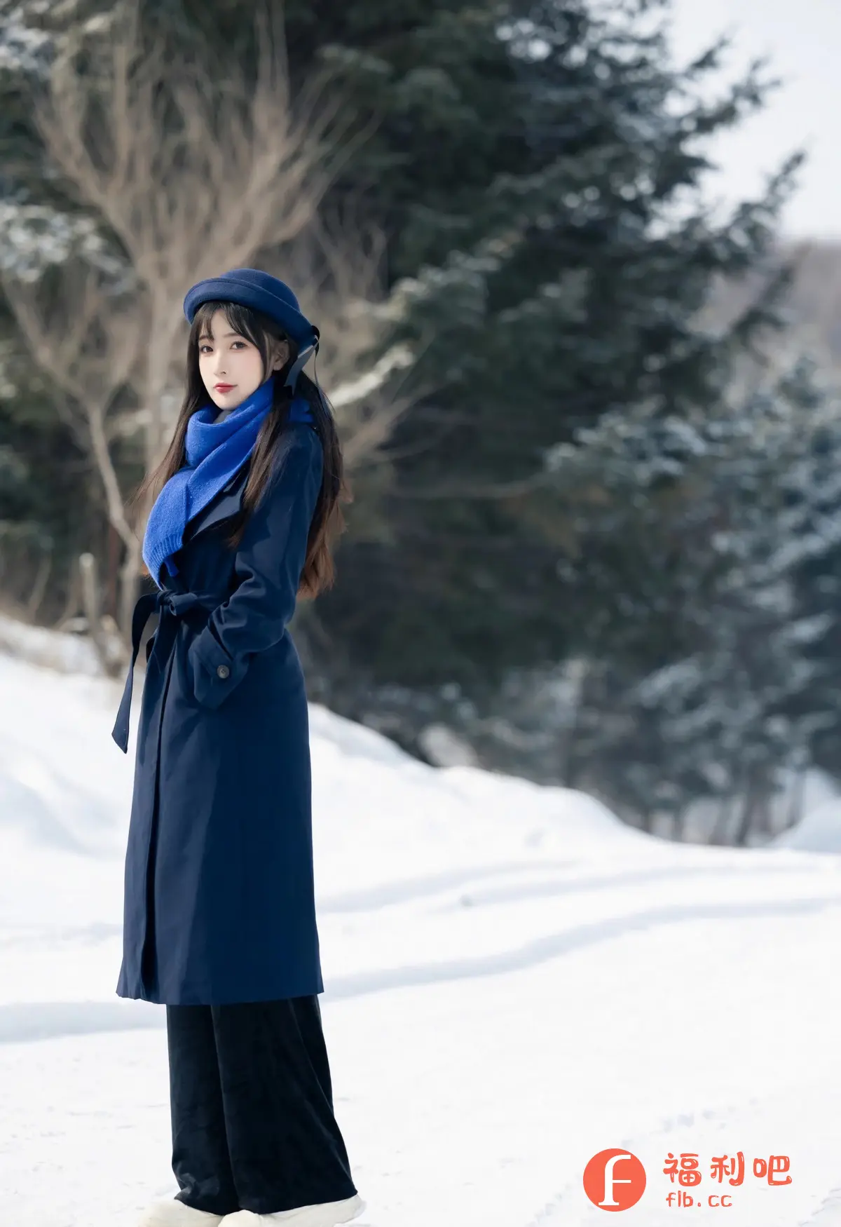 画面中一位年轻女子站在一片雪地中,她穿着深蓝色的长款外套,腰间系着腰带,脖子上围着亮蓝色的围巾。头上戴着同色系的帽子,长发披肩,显得非常时尚。她的肤色白皙,妆容精致,眼神略带忧郁地看向镜头,给人一种清新脱俗的感觉。背景是一片被雪覆盖的树林,白雪皑皑,更衬托出人物的清新气质。整体构图简洁,色彩对比鲜明,营造出一种唯美、浪漫的氛围。这是一张具有较高艺术性的写真作品,展示了人物的美丽和雪景的宁静。