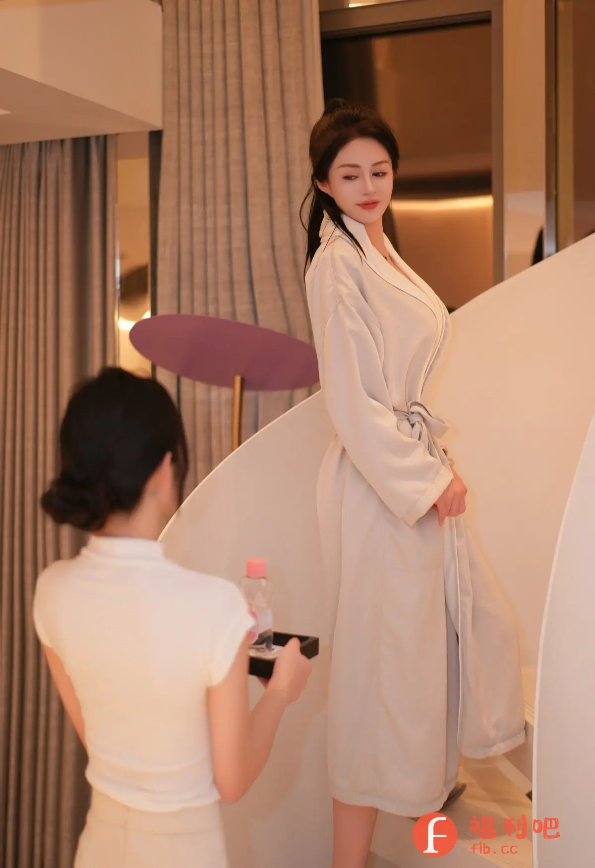 照片中,一位优雅的亚洲女性身穿浅色浴袍,正缓缓走下楼梯。她的头发梳成精致的发髻,露出美丽的颈部线条。在她身后,一位同样穿着浅色服装的女士手持黑色托盘,上面放着一瓶粉色液体,似乎是护肤品,正准备递给浴袍女子。场景显得十分温馨私密,可能是在酒店房间或家中。背景是米色调的窗帘和现代风格的楼梯设计,整体呈现出一种柔和、舒适的氛围。图片展示了女性的柔美和私人的生活场景,营造出一种轻松惬意的氛围。
一位优雅的亚洲女性身穿浅色浴袍,正缓缓走下楼梯。在她身后,一位女士手持黑色托盘,上面放着一瓶粉色液体,正准备递给浴袍女子。