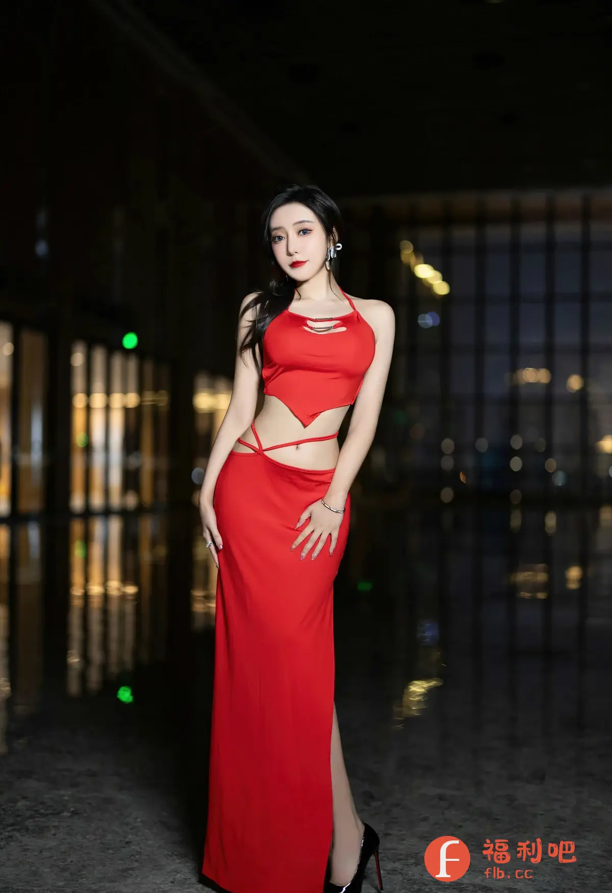 照片中是一位穿着红色时尚连衣裙的美女，她站在一个光线昏暗的室内环境中，背景中有模糊的光点，营造出一种神秘和性感的气氛。连衣裙的设计独特，上半身是一个露脐的吊带上衣，腰部有镂空的设计，下半身是高开叉的长裙，凸显了她的身材曲线。美女化着精致的妆容，红唇非常醒目，戴着闪亮的耳环，一头乌黑的长发随意地披在肩上。她的姿势优雅，一只手轻轻地放在腰间，另一只手自然地垂下，展现出自信和魅力。整体构图和光线处理都非常专业，给人一种高品质的视觉享受。

照片中是一位穿着红色时尚连衣裙的美女
