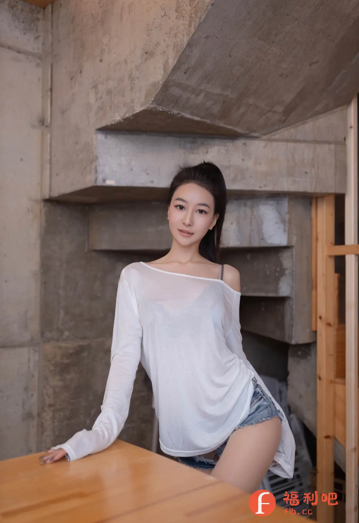 这位年轻的亚洲女性身着休闲装,拍摄了一张迷人的私房写真。她穿着一件宽松的白色长袖上衣,隐约可见内搭的黑色内衣肩带,搭配一件牛仔短裤,展现出一种随性而性感的魅力。她的长发被梳成高马尾,露出精致的五官,皮肤白皙,眼神温柔。她倚靠在一个木质桌子旁,背景是粗犷的混凝土墙面,这种工业风格的背景与她柔美的气质形成了鲜明的对比,增加了照片的视觉吸引力。整体构图简洁,光线柔和,突出了女性的自然美和自信气质,营造出一种轻松舒适的氛围。