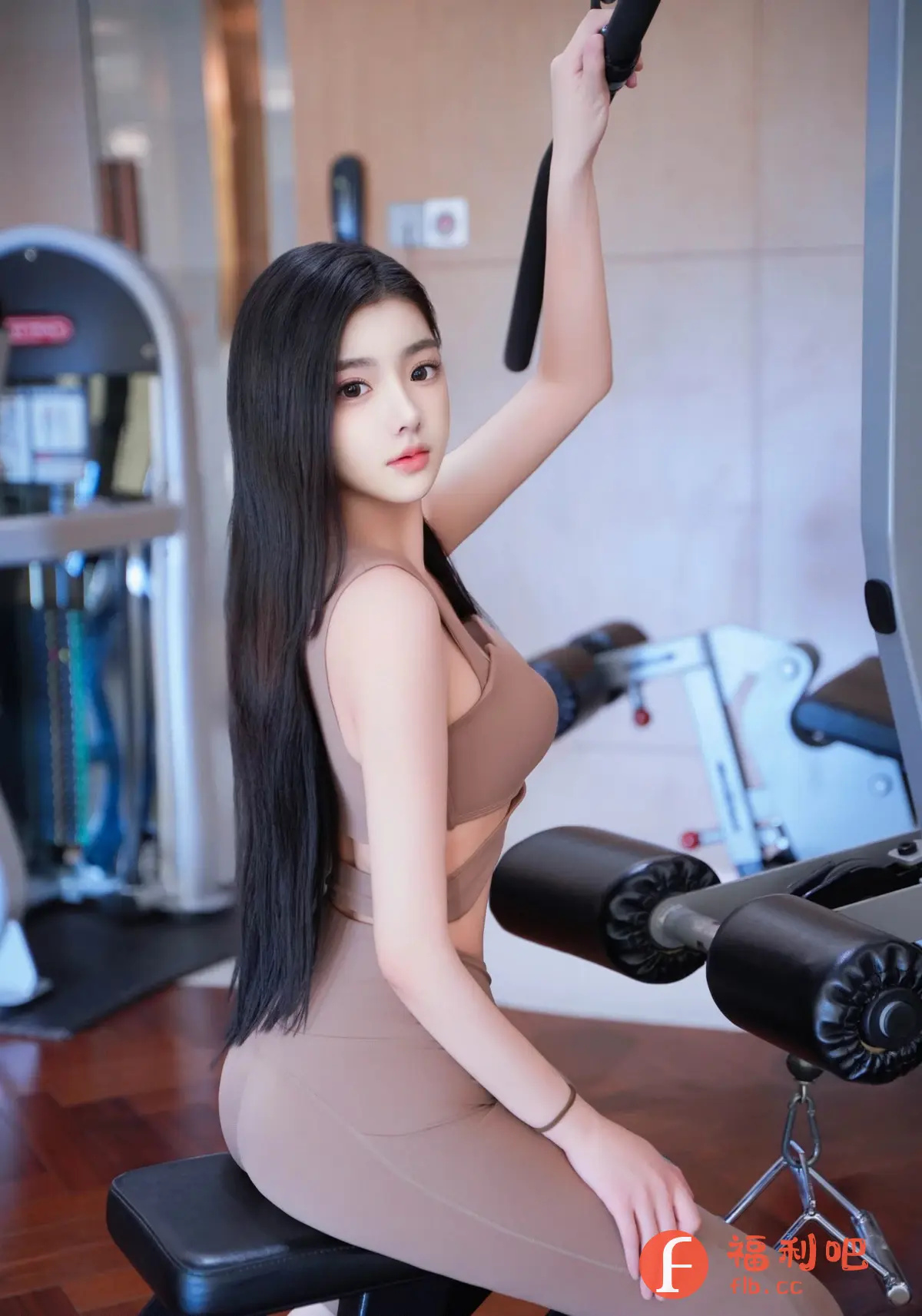 一位年轻漂亮的亚洲女性在健身房锻炼。她穿着一套棕色的运动服,上身是露脐的运动内衣,下身是紧身瑜伽裤,完美地展现了她纤细的腰肢和修长的身材。她长发披肩,皮肤白皙,五官精致,看起来非常迷人。她坐在一个器械上,正用手拉着拉杆,专注地做着训练。健身房的环境看起来很专业,各种健身器材整齐地摆放着。整个画面充满了健康、活力和美丽的气息。