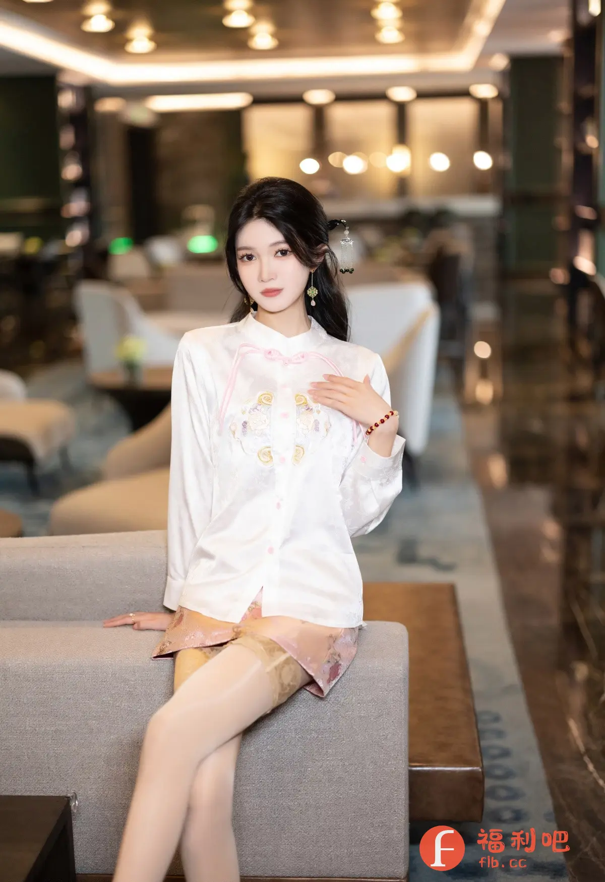 这张照片展现了一位充满东方韵味的美女,她身穿一套精致的白色中式上衣,衣襟上绣有淡雅的花纹,领口系着粉色的丝带,细节之处彰显着她的品味。下身搭配一条粉色印花短裙,更增添了一丝俏皮与活泼。她优雅地坐在沙发上,一双穿着丝袜的美腿交叠着,姿态妩媚动人。她的妆容精致,眉目如画,眼神中透露着温柔与自信。头上的发饰与耳饰也与整体造型相得益彰,更衬托出她的古典气质。背景是豪华的室内环境,柔和的灯光洒在她身上,营造出一种温馨而浪漫的氛围。整体来看,这张照片不仅展现了美女的美丽外貌,更体现了她优雅的气质和独特的风格。