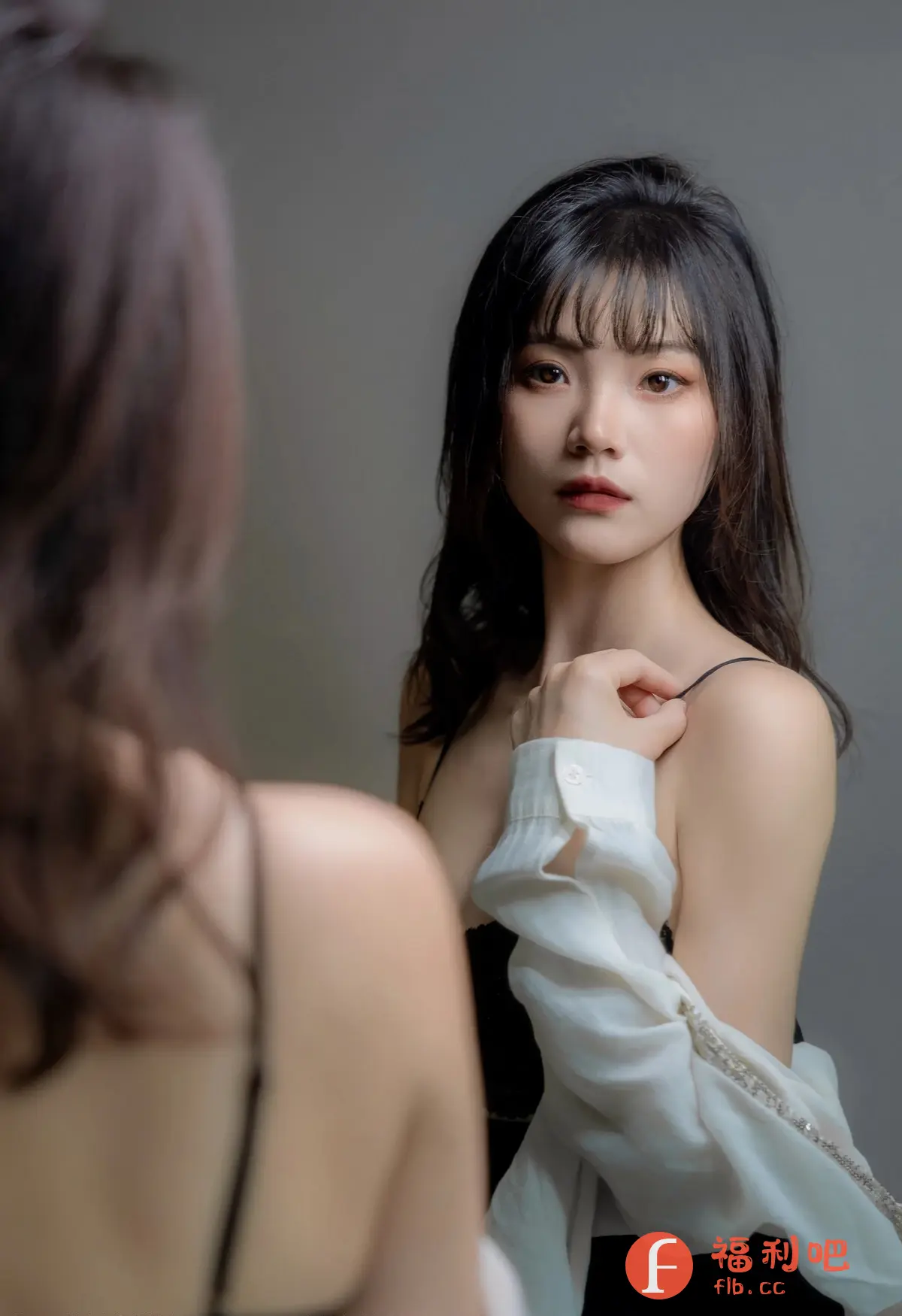 这张私房写真捕捉到一位年轻女性的迷人瞬间,她正对着镜子,眼神带着一丝忧郁和自信。柔和的光线照亮了她精致的五官,凸显了她的红唇和清澈的眼睛。她穿着一件黑色吊带,外面随意地披着一件白色衬衫,展现出一种慵懒而性感的风格。镜子中的倒影增添了一层神秘感,仿佛她在审视自己不同的面向。背景简约而干净,更加突出了人物本身的美丽和气质。这不仅仅是一张照片,更像是一幅艺术品,展现了女性的魅力和内心的情感。
