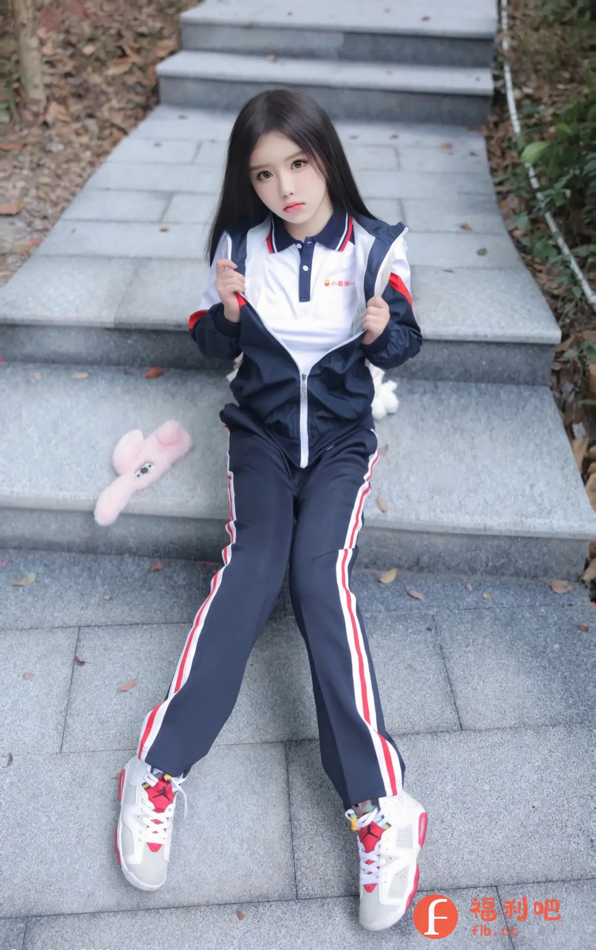 这是一位年轻女性,她正在漫步在阶梯上,穿着黑色和白色的运动服装。她的头发是浓密的黑色,她的笑容显示她的愉悦和自信。她的手掌在她的腹部,她的腿轻轻摇曳。她的衣服和运动鞋都是黑色和白色的配色,给她一种时尚和优雅的感觉。