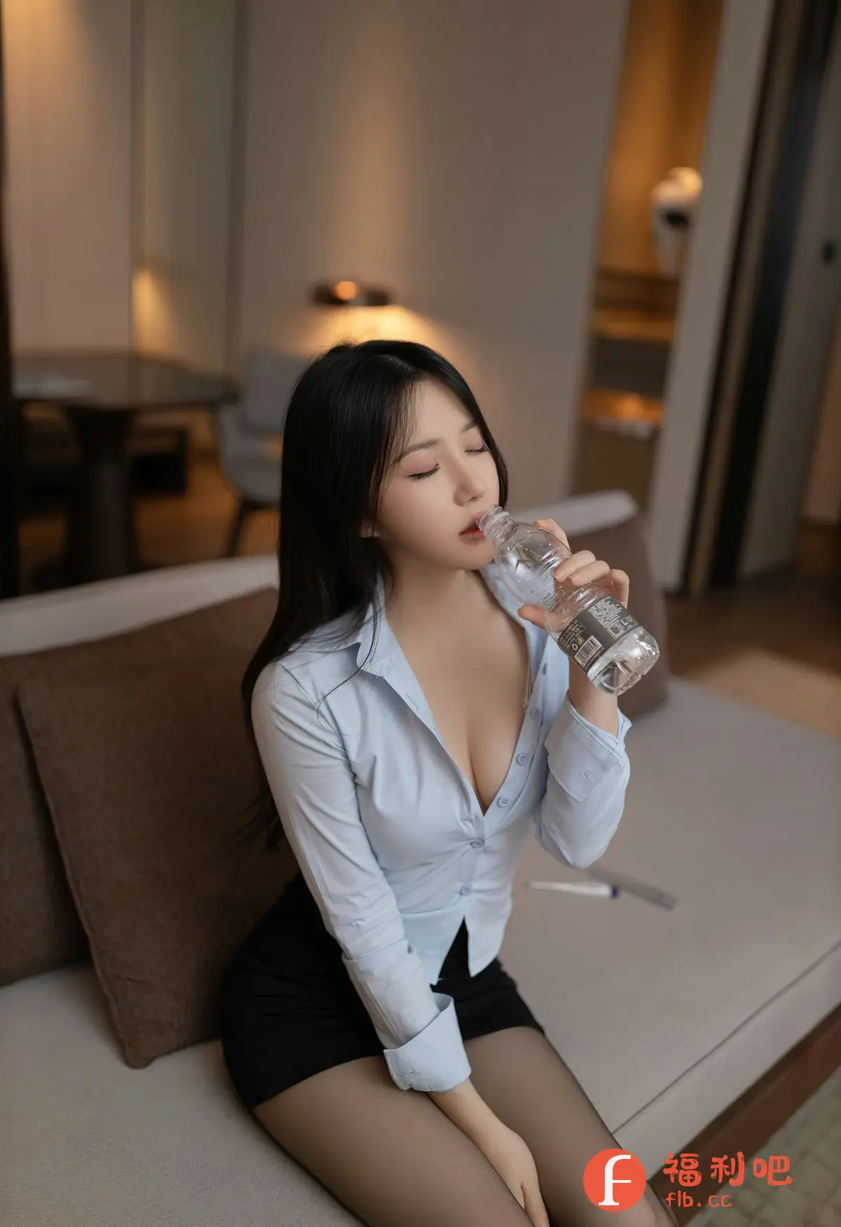 这张照片展现了一位优雅迷人的亚洲女性。她有着一头乌黑亮丽的长发,白皙的肌肤,精致的五官,以及诱人的红唇。她身穿一件浅蓝色的衬衫,搭配一件黑色的短裙,显得既性感又不失干练。她的衬衫领口微微敞开,露出了迷人的锁骨和事业线。她坐在一个米色的沙发上,手拿一瓶矿泉水,正在优雅地喝水,闭着眼睛,似乎非常享受这一刻的宁静。房间的背景布置简洁而温馨,柔和的光线洒在她的身上,营造出一种慵懒而舒适的氛围。整体而言,这张照片散发出一种成熟女性的魅力和自信。
