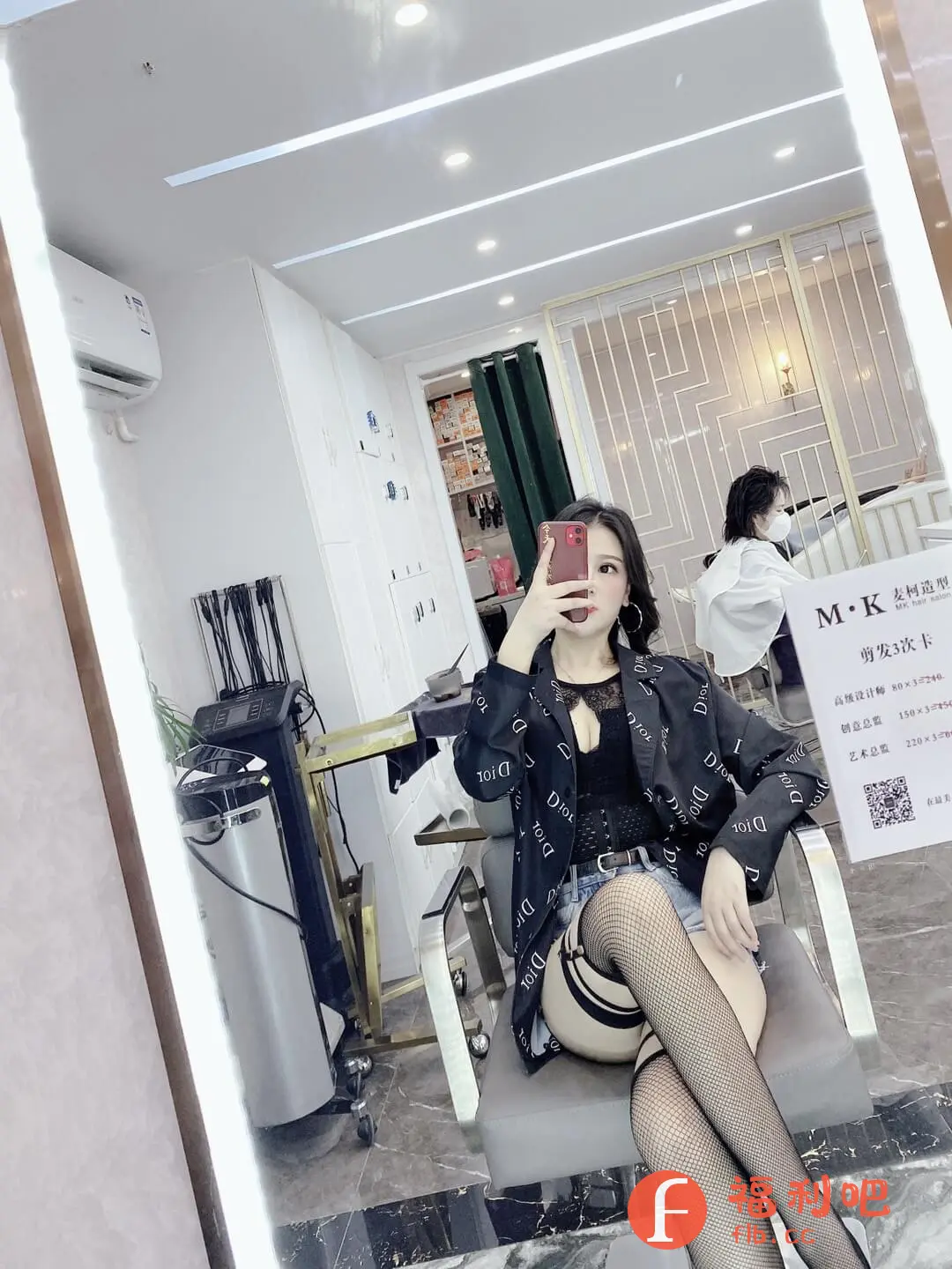 描述:这位美女身穿一件印有“DIOR”字样的黑色外套,内搭一件黑色蕾丝内衣,下身搭配一条牛仔短裤和黑色渔网袜,性感又时尚。她坐在一个旋转椅上,对着镜子自拍,背景是一家美发沙龙,灯光明亮,环境整洁。她的妆容精致,头发乌黑亮丽,整个人看起来自信满满。从镜子中还可以看到,沙龙里还有其他顾客和工作人员。这张照片整体给人一种时尚、性感、精致的感觉,很有吸引力。