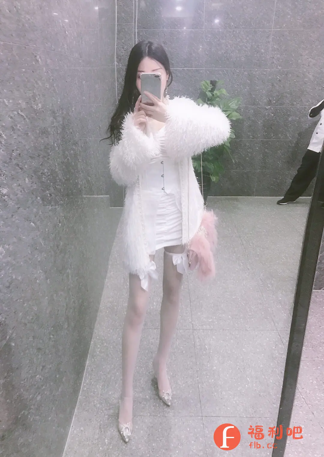 这位美女身穿一套精致的白色套装,在镜子前自拍,展现她的甜美风格。套装包括一件紧身胸衣款式的上衣和一条短裙,勾勒出姣好身材。外搭一件毛茸茸的白色外套,增添了温暖和梦幻感。腿上穿着白色丝袜,配有可爱的白色蝴蝶结装饰,更显少女情怀。脚踩一双闪闪发光的银色高跟鞋,为整体造型增添了一丝奢华感。她拿着手机遮住脸,更显神秘感。整体穿搭风格甜美可爱,非常适合约会或参加派对。