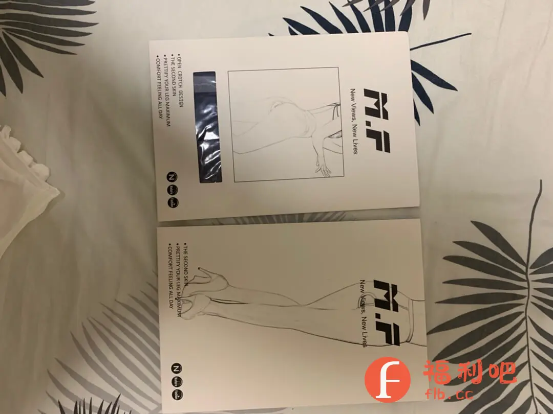 两盒包装简洁的商品并排放置在带有植物花纹的床单上,盒子上印着“M.F New Views, New Lives”的字样,以及手绘风格的人体腿部和躯干线条图。其中一个盒子还特别标注了产品的特点:“OPEN CROTCH DESIGN(开档设计”、“THE SECOND SKIN(第二层肌肤”、“PRETTIFY YOUR LEG MAXIMUM(修饰腿部线条”、“COMFORT FEELING ALL DAY(全天舒适”。整体包装给人一种简约而注重功能性的感觉,突出了产品的舒适度和塑形效果。考虑到“开档设计”等关键词,推测这是某种内衣或者塑形衣裤的产品。
