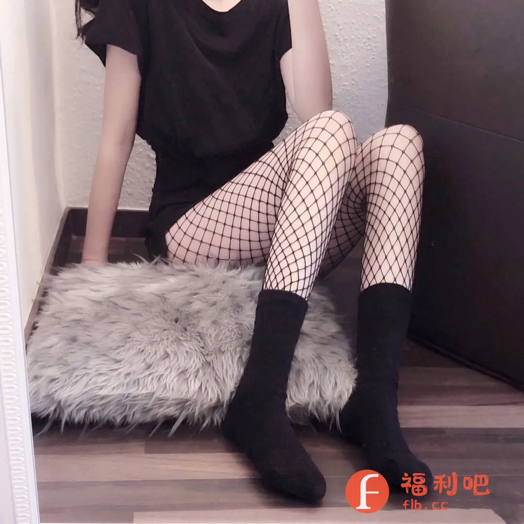 描述：这位美女展示了一套暗黑系穿搭，黑色T恤搭配短裙，性感又带点神秘。最吸睛的是她穿的黑色渔网袜，在视觉上拉长了腿部线条，更显纤细。脚上搭配一双黑色中筒袜，既保暖又增添了层次感。她慵懒地坐在一个毛茸茸的垫子上，整个画面散发着一种随性又时尚的气息。地板是深棕色的，背景墙是米白色的，整体色调偏暗，更突出了穿搭的个性。这身搭配很适合喜欢酷酷风格的女生，简约而不简单，轻松打造时尚感。