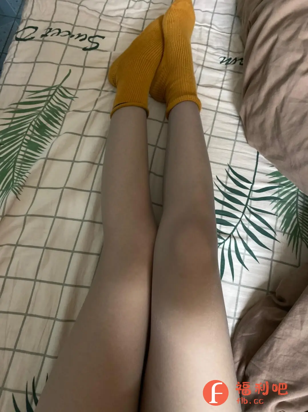 一位美女躺在床上,展示了她的腿和穿着的黄色袜子。床单是格子花纹,上面印有绿色的叶子图案,整体风格清新自然。从照片的角度来看,应该是自拍,展现了轻松舒适的居家氛围。穿着黄色袜子,可能想展示袜子款式或颜色搭配。买家秀通常用于展示购买的商品,所以这很可能是袜子或者床单的买家秀。整体来说,这张照片的重点在于展示腿部和袜子,背景的床单也起到了一定的衬托作用,让画面更加丰富。无论是展示商品还是分享生活,这张照片都传达了一种惬意和时尚感。