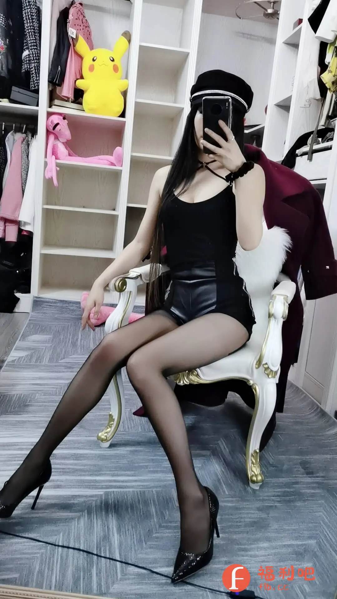 一位时尚美女分享了一张买家秀，她身穿黑色吊带上衣搭配黑色皮短裤，脚踩黑色高跟鞋，尽显性感妩媚。她戴着一顶潮流的黑色帽子，手拿手机自拍，挡住了脸，更增添了一丝神秘感。背景是一个摆满衣服和玩偶的衣柜，营造出一种温馨舒适的氛围。整体搭配简约而不失时尚感，展现了美女的好身材和独特的穿搭品味。这张照片无论是从服装搭配还是拍摄角度都十分吸引人，让人忍不住想了解同款的购买链接。无疑，这是一张成功的买家秀，能有效吸引潜在顾客的目光。