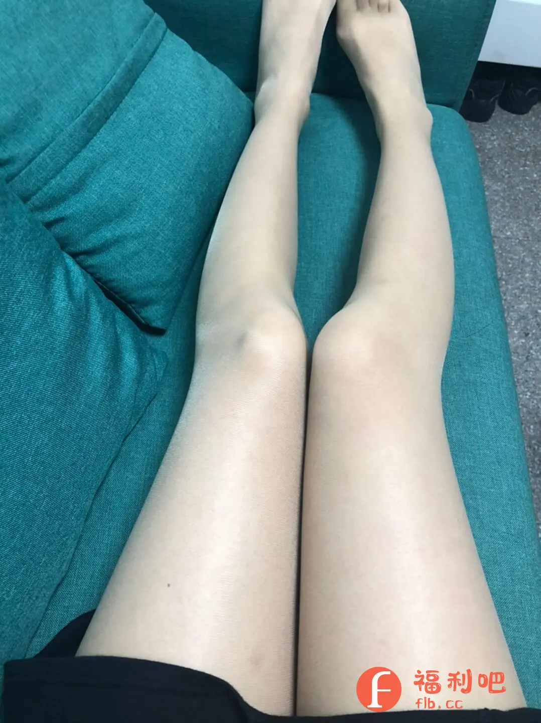这张图片展示了一双穿着肉色丝袜的美腿,主人正舒适地躺在绿色的沙发上。从视角来看,这应该是拍摄者从上往下俯视的角度。双腿并拢,笔直地放置在沙发上,丝袜的质感细腻,颜色均匀,显得双腿更加白皙修长。沙发的材质看起来柔软舒适,整体画面给人一种放松惬意的感觉。黑色衣物露出一角,可能穿着深色系的衣服。背景中还能隐约看到一些黑色的鞋子,增加了画面的生活气息。这是一张常见的展示身材和丝袜效果的照片,可能用于分享穿着体验或展示商品的特性。