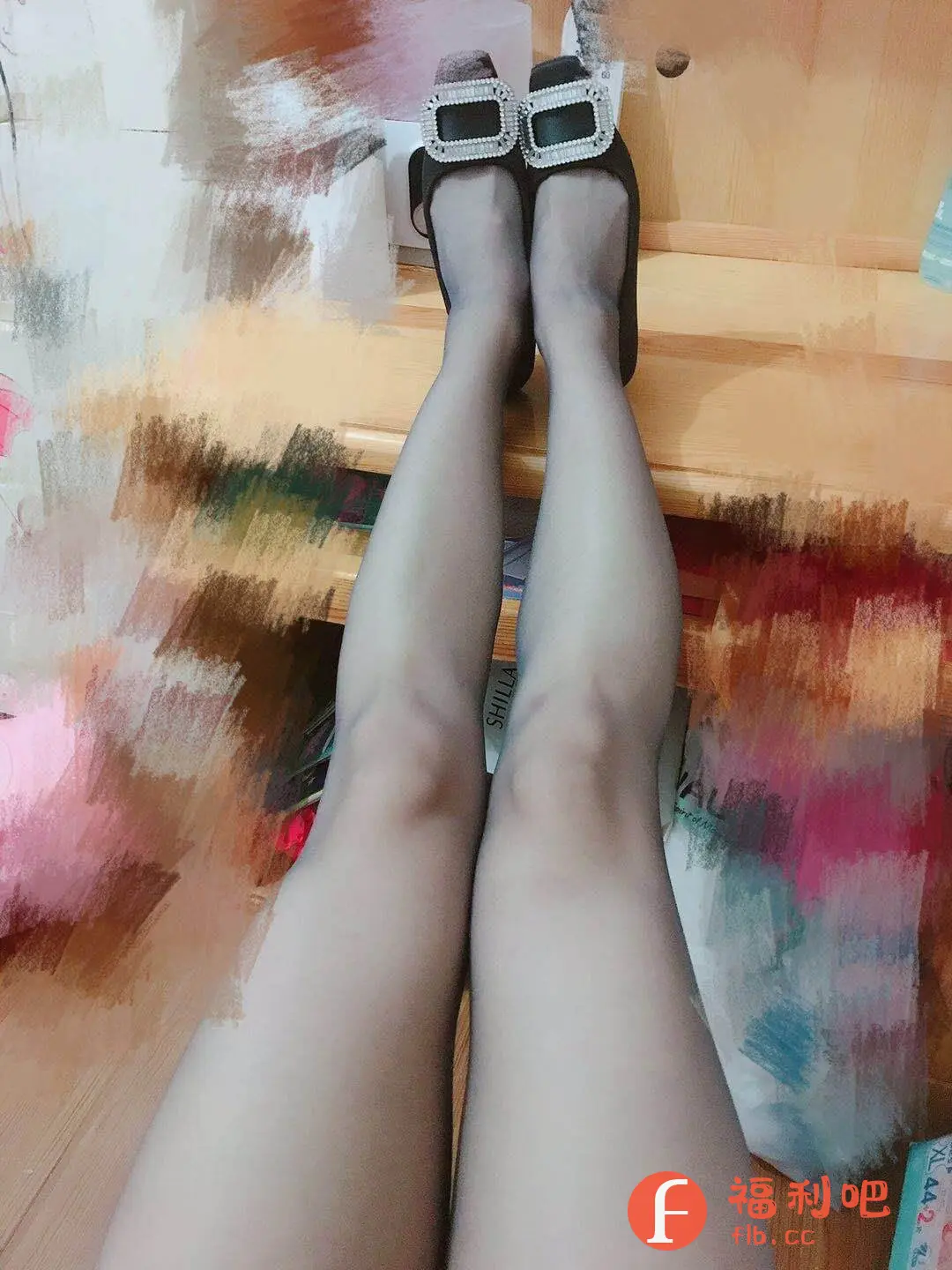 这张图片展示了一双穿着黑色丝袜的腿,穿着一双带有大方扣装饰的黑色鞋子。拍摄角度是从上往下,腿部笔直伸展,营造出一种视觉上的延伸感,显得腿部修长。背景看起来像是一个房间的角落,有木质的家具,还有一些杂物堆积,整体环境较为生活化。丝袜的颜色较浅,呈现出一种朦胧的性感,而鞋子上的大方扣则增添了一丝时尚感和亮点。这张图片很可能是在展示这双鞋子或者丝袜的穿着效果,尤其适合在电商平台上作为买家秀或者商品展示图使用,能够直观地展现商品的实际穿着效果和质感。