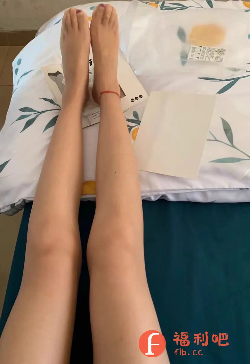 这张买家秀展示了一双穿着丝袜的美腿。美女平躺在床上,双腿笔直伸展,脚上涂着紫色指甲油。腿部肌肤白皙细腻,丝袜更增添了一份朦胧美感。旁边放着丝袜的包装盒和一张白色的卡片,可能是购物凭证或优惠券。床单是清新的植物印花图案,与整体画面风格相协调。买家秀的重点在于展示丝袜的上身效果,让其他买家可以更直观地了解产品的质感和穿着体验。整体构图简洁,色彩柔和,给人一种舒适自然的感觉。