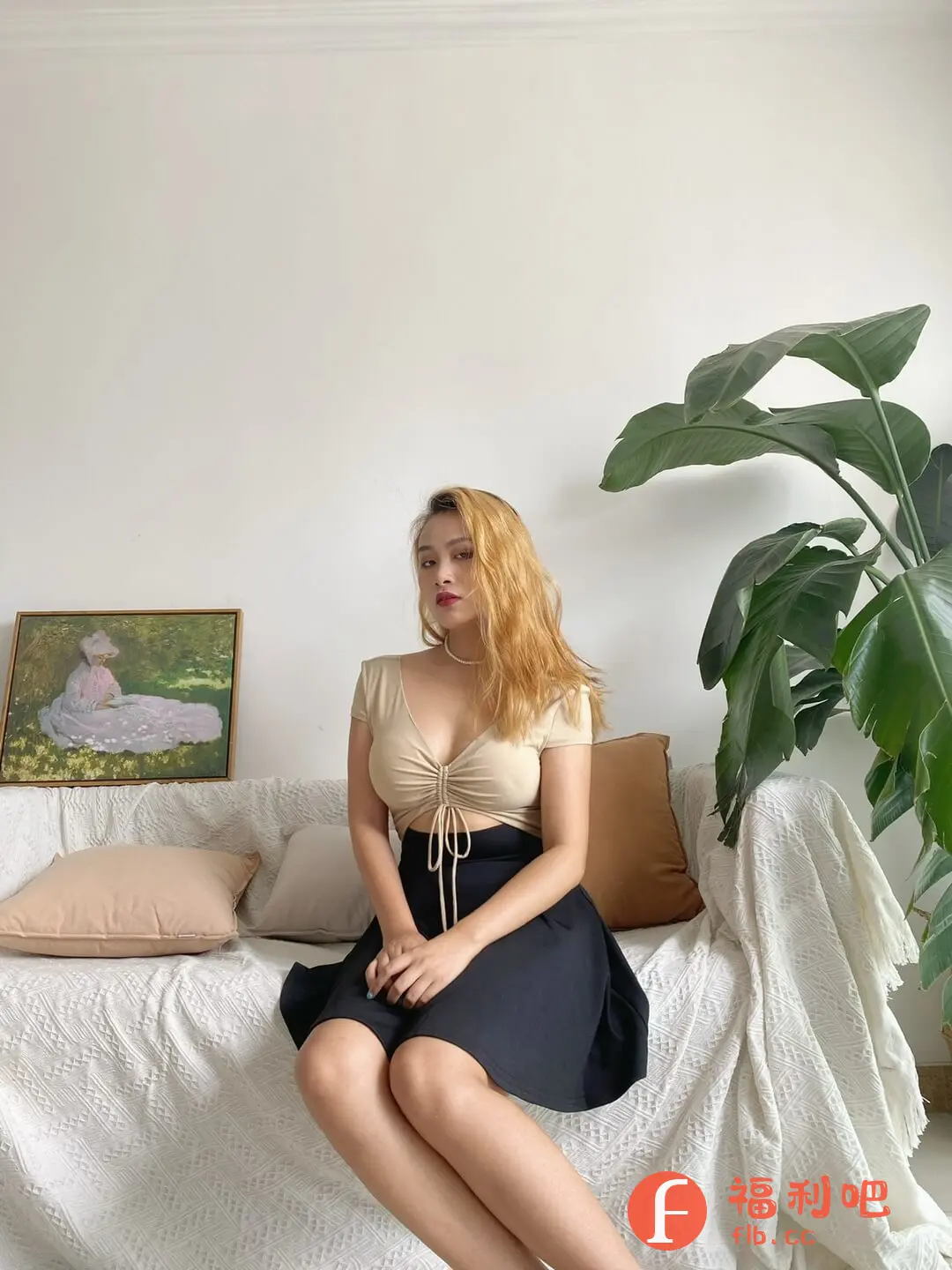 这位女士穿着时尚,展示了一套别致的两件套服装。上身是一件米色短款上衣,设计独特,在胸前有抽绳细节,略微露腰,凸显了身材的曲线美。下身搭配了一条黑色A字短裙,简洁大方,裙摆的蓬松感增添了一丝活泼。她坐在一个装饰温馨的白色沙发上,沙发上有几个米色和棕色的抱枕,背景墙上挂着一幅画作。旁边摆放着一盆郁郁葱葱的绿色植物,整体营造出一种舒适、休闲又充满时尚感的生活氛围。整个搭配既凸显了女性的柔美,又不失个性与活力,非常适合日常穿着或休闲场合。