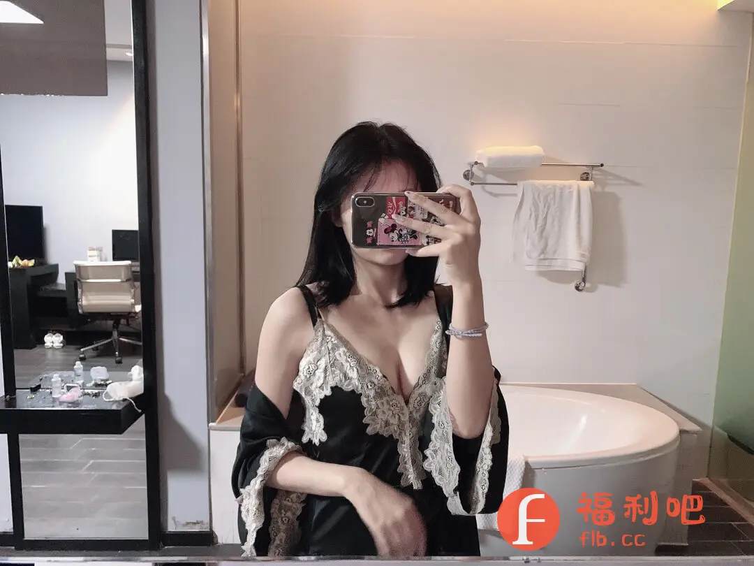 这位美女身穿黑色蕾丝睡衣,在浴室自拍。睡衣款式性感,深V设计凸显身材,蕾丝花边增添了精致感。她手持手机挡住脸,手机壳是可爱的卡通图案,露出纤细的手臂和手腕上的手链。浴室背景简洁明亮,有浴缸、毛巾架和干净的白色墙面。整体画面充满生活气息,展现了居家放松的状态。睡衣的材质看起来柔软舒适,适合睡前穿着。从照片细节可以看出,这位美女对生活品质有一定追求,注重细节和个人形象。