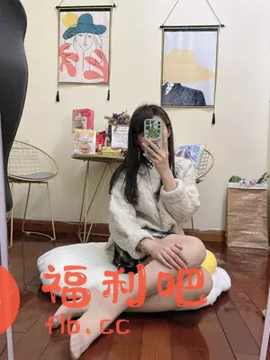 一位穿着米白色麻花毛衣的美女坐在一个白色的圆形软垫上,她穿着肉色的丝袜,双腿交叉,显得非常休闲舒适。她手里拿着手机,似乎正在自拍或者拍摄买家秀。背景墙上挂着两幅装饰画,一幅是戴着绿色帽子的女人画像,另一幅是戴着黄色帽子的画像。画的前面有一张小圆桌,桌上摆放着一些零食和装饰品,增添了生活气息。房间的角落里放着一把金色的椅子,旁边还有一个棕色的纸袋,上面似乎还装饰着一些绿植。整体画面温馨和谐,展现了美女惬意的居家生活状态。