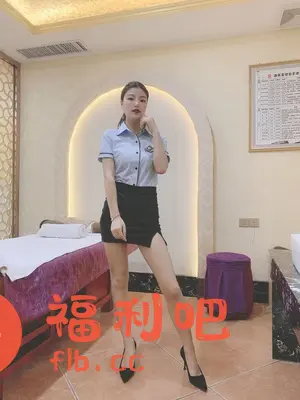 一位年轻漂亮的亚洲女性站在一个装修精致的房间里,她身穿浅蓝色短袖衬衫和黑色短裙,脚穿黑色高跟鞋,摆出自信的姿势。房间里有一张按摩床,一个紫色的小凳子,墙上还有一个装饰性的拱门和一幅挂画,整体环境给人一种舒适放松的感觉。女性的服装和环境暗示这可能是一个美容或按摩场所,而她的装扮可能是一种职业制服。
