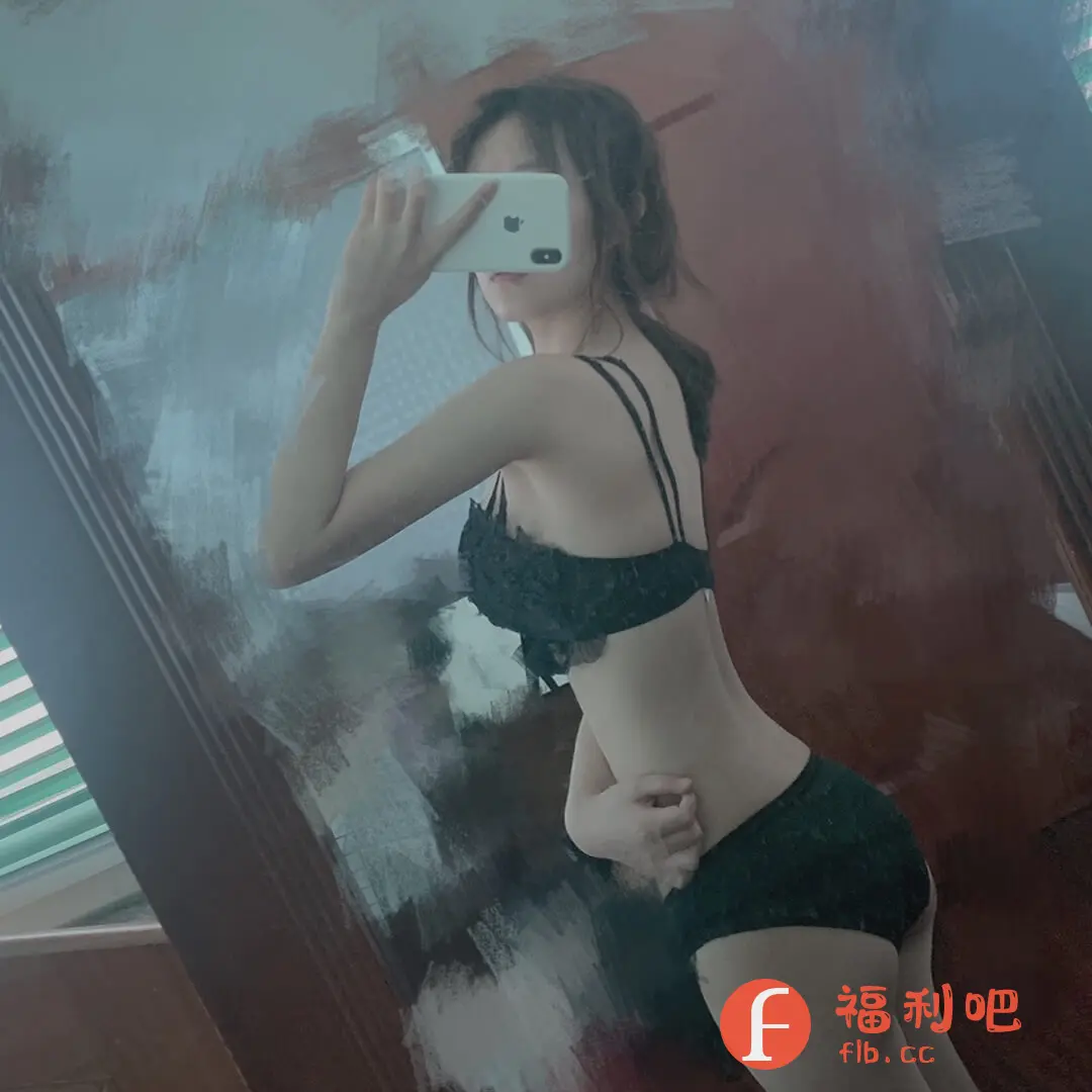 描述:一位身材苗条的亚洲女性在室内对着镜子自拍,展示一套黑色蕾丝内衣。她手持白色手机遮住脸部,只露出部分头发。内衣款式性感,胸罩带有精致的蕾丝花边和细肩带,短裤也是黑色蕾丝材质,贴身显身材。背景模糊,能看到一些家居陈设,但重点突出了内衣的细节和穿着效果。整体风格偏向私密和性感,很可能是该内衣产品的买家秀照片,旨在展示产品的真实穿着效果,给其他买家提供参考。照片的色调偏柔和,光线也比较自然。
