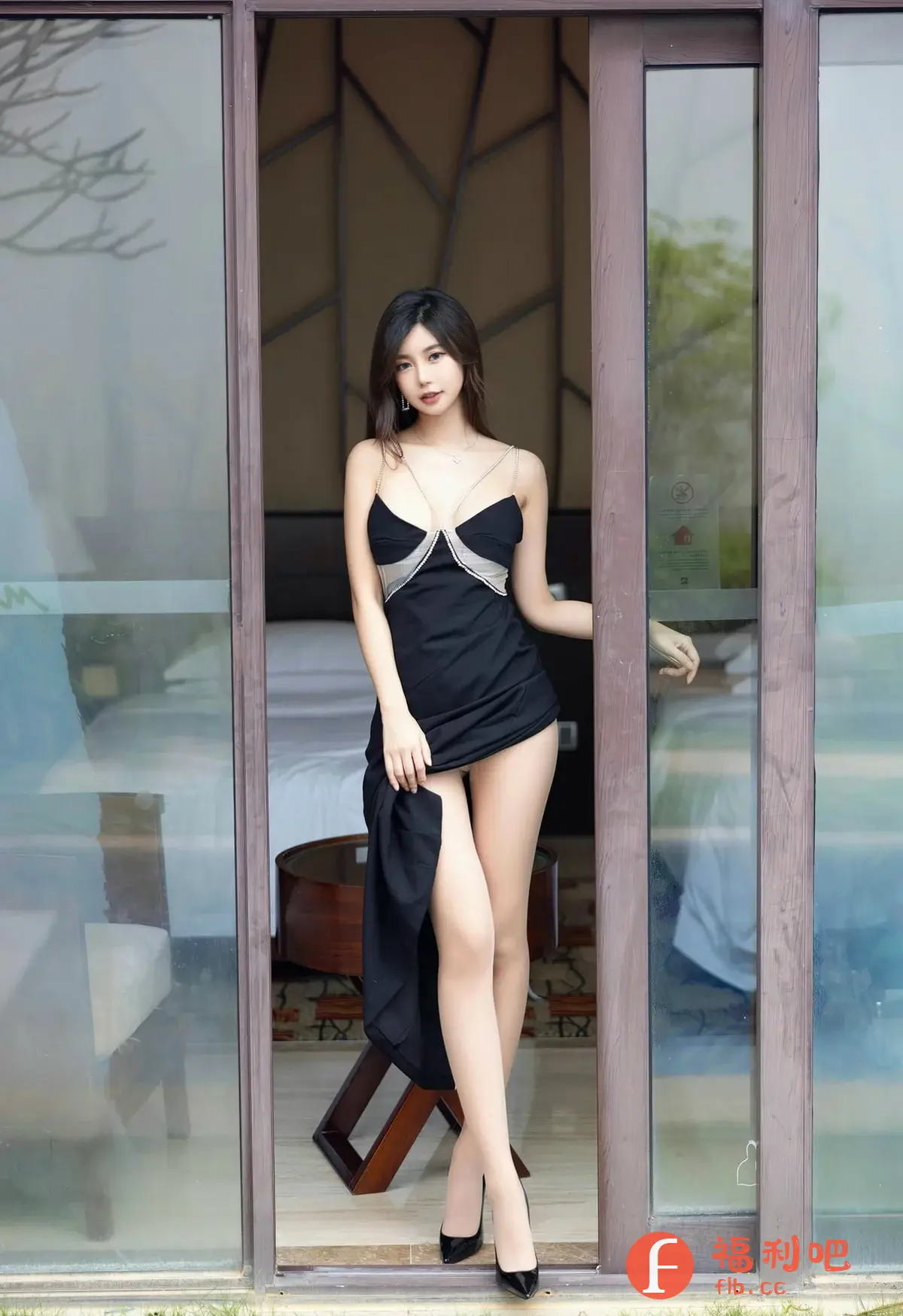 描述:照片中,一位身材姣好的年轻女子身穿一件黑色吊带连衣裙,裙子设计独特,领口处以银色亮片装饰,增添了一丝性感与华丽感。她站在一个看起来像是酒店房间的玻璃门前,透过玻璃可以看到房间内部的布置,包括床、小桌子等。女子一手轻轻提起裙摆,露出修长的双腿,脚上搭配一双黑色高跟鞋,更显气质优雅。她的妆容精致,长发披肩,眼神妩媚,整体造型充满诱惑力。照片的背景虚化处理,更加突出了人物本身,营造出一种私密、性感的气氛。